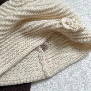 Detail showing the 100% wool material and knitted flower on this white beanie