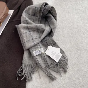 Macro detail of grey plaid 100% wool scarf with soft fringe and white fabric label