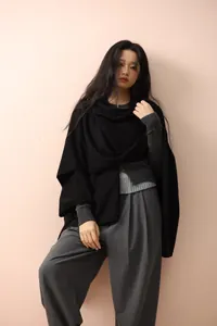 Minimalist black knit cape poncho styled with grey trousers for an elegant autumn look
