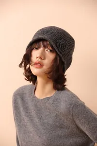 Close-up detail of dark grey knit beanie featuring a delicate handmade crochet flower