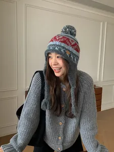 Détail du bonnet en tricot à motif nordique avec grand pompon et cache-oreilles tressés