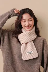Detailed close-up of cream knit wool scarf with vertical ribbed texture and brand label