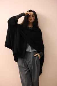 Detail of elegant black knitted poncho shawl showing soft drape and premium texture