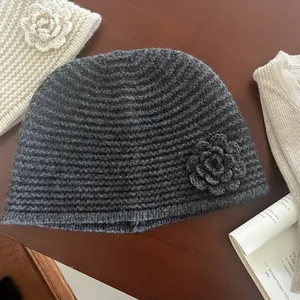 Detail of dark grey knit beanie featuring a handmade crochet flower and thick ribbed texture