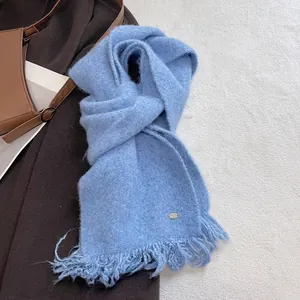 Detail of light blue knit scarf featuring soft wool blend texture and long fringe tassels