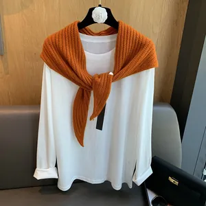Détail d'un châle en laine orange avec un tee-shirt blanc à manches longues
