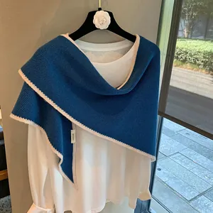 Detalle de etiqueta 100% lana y borde de ganchillo blanco en el chal azul