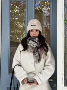 Detail of wool plaid tassel scarf paired with cream sherpa jacket and knit beanie