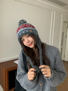 Détail du bonnet d'hiver en tricot avec pompon, cache-oreilles et motifs jacquard colorés