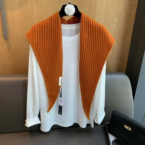 Détail du châle en maille 100% laine orange vif montrant la texture côtelée et l'étiquette