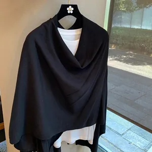 Detail of a black knit shawl with natural drape and texture over a white T-shirt