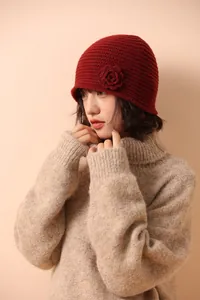 Close-up of deep red knit beanie with handmade 3D floral accent and thick weave texture
