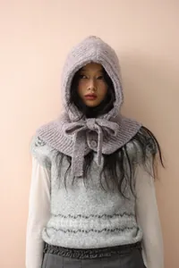 Detail of lavender knitted balaclava hood featuring a bow tie and single button closure
