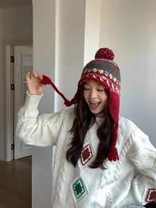 Détail du bonnet en tricot avec pompon rouge, motif jacquard et protège-oreilles