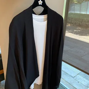 Detail of a black knit cardigan layered over a white t-shirt in a modern casual style