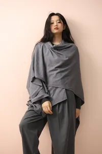 Detail of grey knit poncho cape showing the soft irregular hem and layered texture