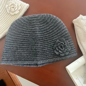 Detail of dark grey knit hat with 3D crochet flower and textured wavy weave pattern