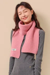 Close-up of pink wool knit scarf showing thick ribbed texture and brand label