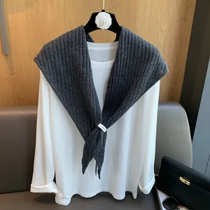 Détail d'un châle en laine gris foncé avec motif à chevrons ajouré sur un t-shirt blanc