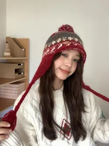 Détail du bonnet en maille ethnique avec pompon et protège-oreilles aux tons rouges