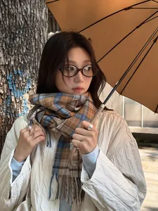 Close-up of wool plaid scarf with fringes styled with a quilted jacket and an umbrella