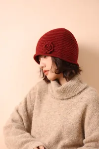 Detailed close-up of dark red crochet knit hat featuring a 3D handmade floral decoration