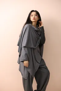 Detail of dark grey knit poncho featuring high-end irregular drape and soft wool texture