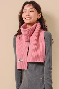 Detail of pink knitted wool scarf featuring thick rib knit texture and premium brand label