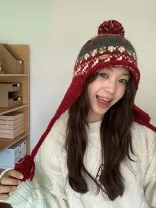 Détail du bonnet en maille jacquard ethnique avec pompon rouge et oreillettes à glands