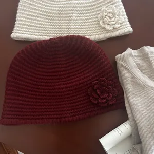 Detail of cream and burgundy knitted beanies with handcrafted crochet flower decorations