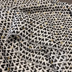 Detail of soft white cotton scarf with black and gold foil hearts and fringe edges