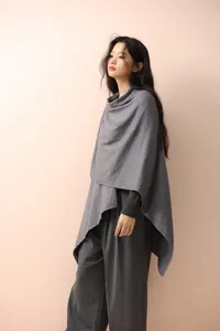 Side view of elegant grey knitted poncho showing draped silhouette and soft knit fabric
