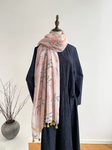 Detail of pink cotton scarf with floral print and yellow tassels on denim dress