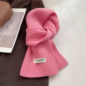 Detailed texture of pink knit wool scarf with a white woven brand logo label