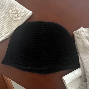 Detailed close-up of handmade crochet flower on black knit beanie with wavy texture