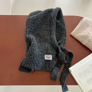 Detail of dark grey knitted Balaclava scarf with a decorative white woven label