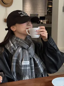 Close-up of grey plaid wool scarf with fringes and black embroidered baseball cap