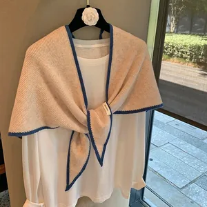 Chal de punto 100% lana beige con ribete azul, mostrado con un nudo frontal elegante