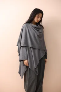 Detail of grey knitted shawl showing the high collar texture and elegant asymmetric hem