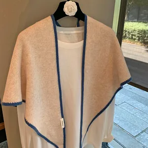 Chal triangular de 100% lana beige con borde de contraste azul en una percha
