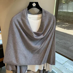 Detail view of premium grey knitted shawl with soft texture draped on a black hanger