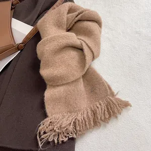 Close-up of warm camel wool blend knit scarf with long tassels and small metal tag