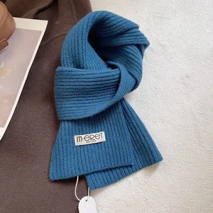Detailed view of blue rib-knit wool scarf with branded woven label and circular tag