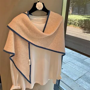 Chal de punto beige 100% lana con ribete azul en contraste sobre camisa blanca de manga