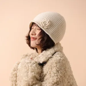Cream knit beanie with crochet flower detail and ribbed texture for a cozy winter look