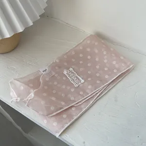 Detaillierte Makroansicht des rosa gepunkteten Netzschals mit zarter Spitzenstickerei und Textur