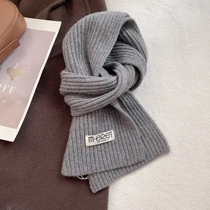 Detailed texture of grey chunky rib knit wool scarf with a minimalist brand label