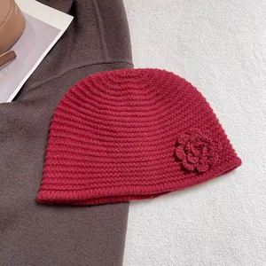 Detailed close-up of dark red ribbed knit beanie with a handmade crochet flower decor