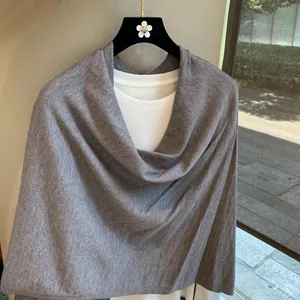 Detail of grey knitted poncho shawl with soft texture over a white t-shirt