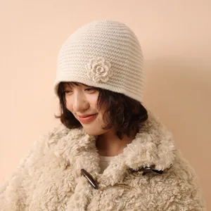 Handmade hollow knit beanie in beige with a floral crochet accent for winter warmth